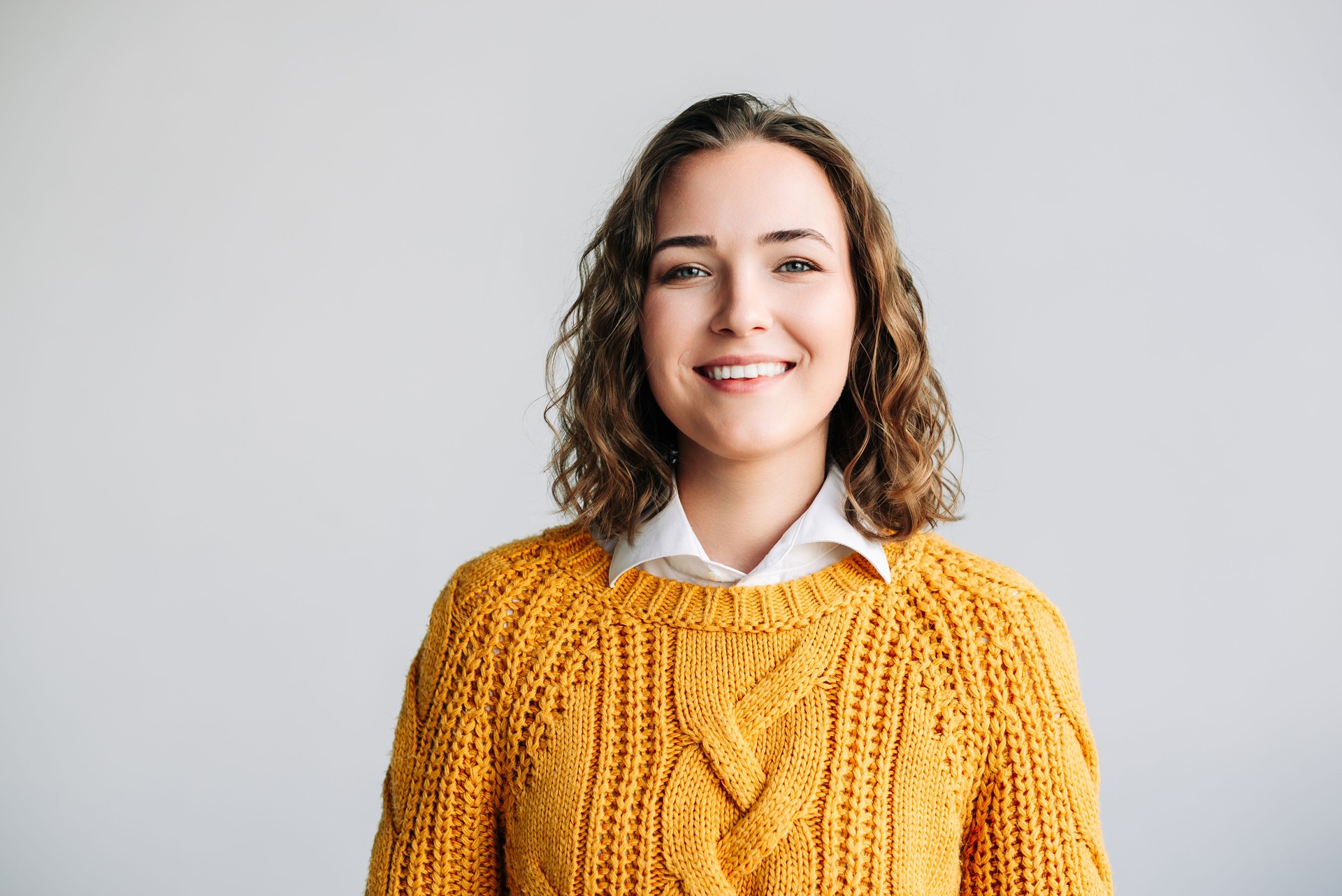 Cheerful Young Woman. Smiling, Positive, and Joyful. Happy Curly-haired Student Laughing, Looking at Camera. Isolated on White Background Close-Up Headshot Portrait for Product and Service Advertising
